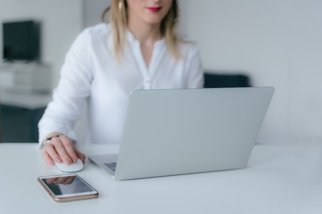 person-working-on-computer-at desk-holding-a-wireless-mouse